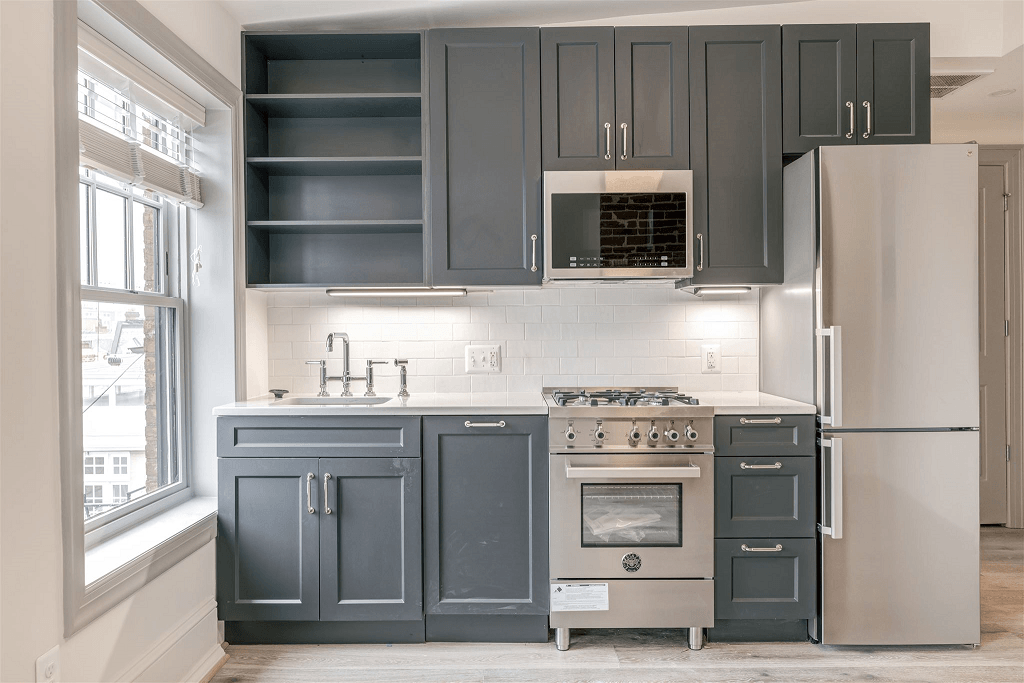 a kitchen with gray cabinets and stainless steel appliances and a window